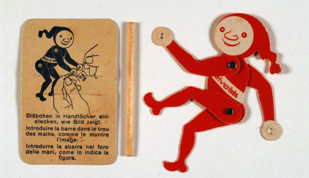  Der turnende rote Knorrli-Akrobat als lustiges, kleines Werbegeschenk aus Karton. 
