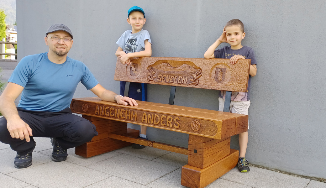 Luis Bartha mit seinen Söhnen und der Sitzbank, die er mit ihrer Hilfe  für die Gemeinde Sevelen geschnitzt hat.