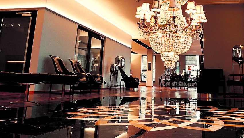 Auffallend in der Empfangshalle: der über drei Stockwerke pendelnde Kristallleuchter und die Marmorintarsien, welche in Form einer Iris gearbeitet sind.