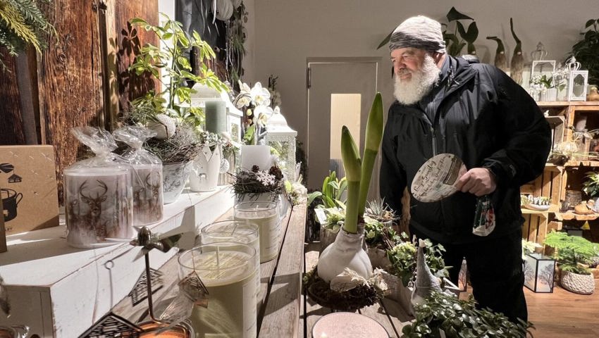  Ein Besucher im Blütenreich in Wildhaus schaut sich das Angebot im Blumengeschäft an und bringt den Flyer für die Auslosung mit.