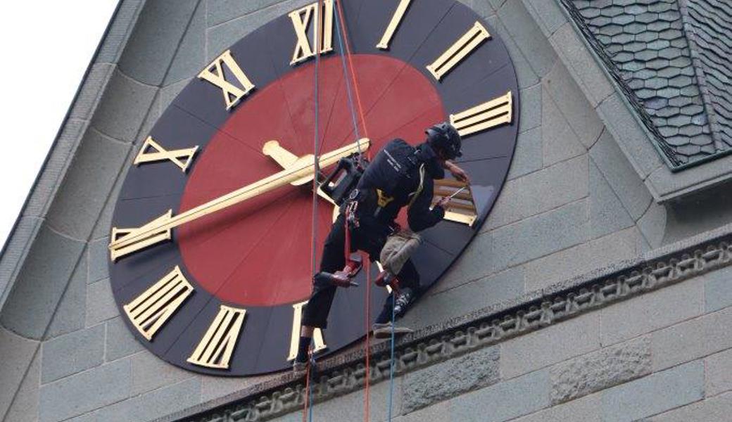 Ein Profi der Grabser Firma Höhenarbeit bei der Reparatur des Zifferblattes in luftiger Höhe.