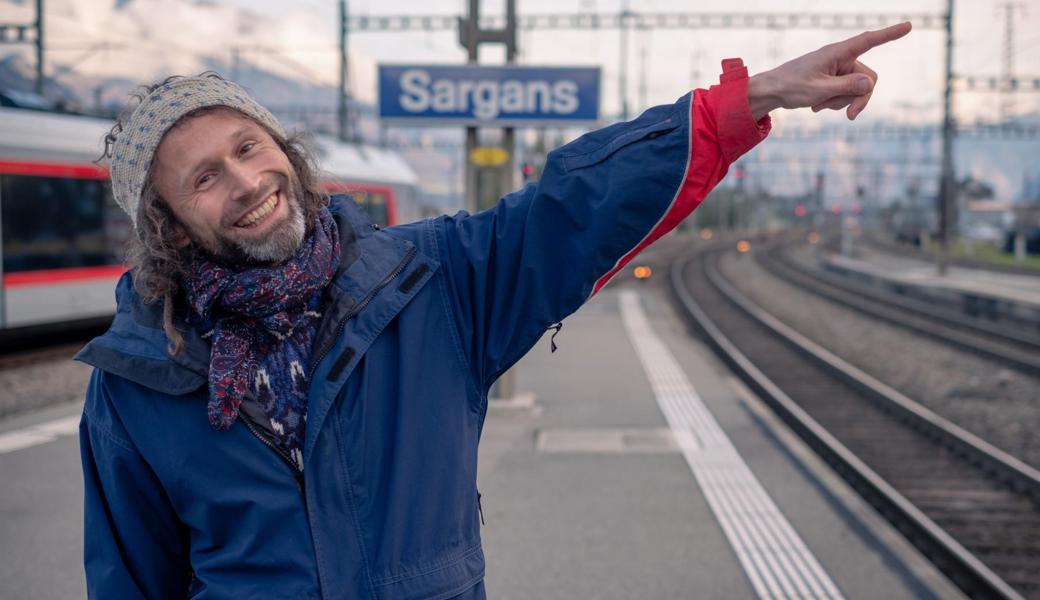 André Götte am Bahnhof Sargans, wo er 2012 Tränen in den Augen hatte, als er nach 15 Monaten auf Weltreise erstmals wieder den Falknis sah. Heute zeigt er am selben Ort in die Ferne, denn wieder steigt das Reisefieber. Wohin es wohl gehen wird?