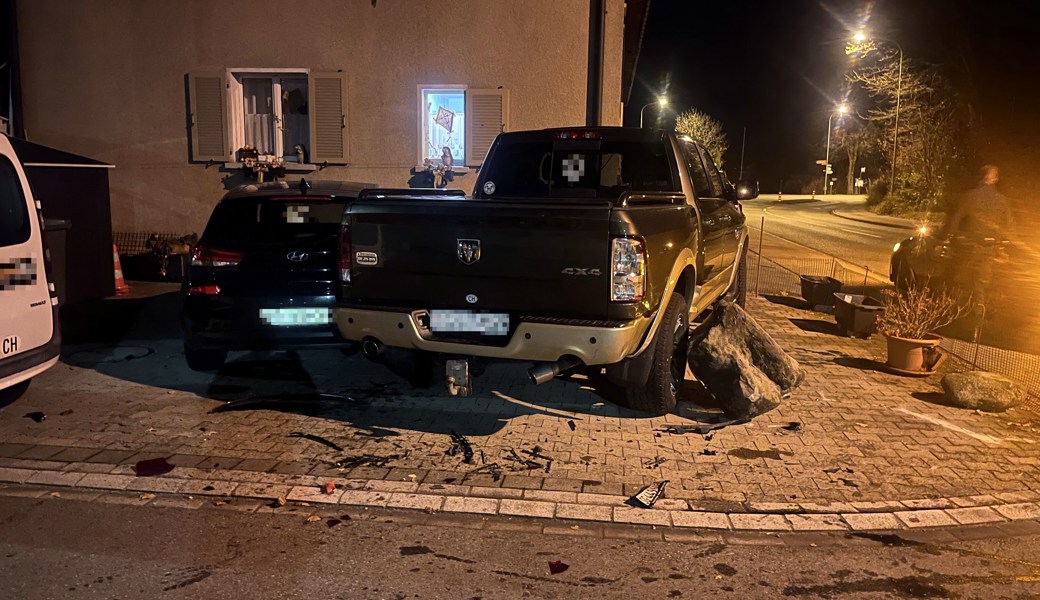 Der Unfallfahrer war wohl recht rassig unterwegs – und donnerte über den Felsbrocken neben dem Parkplatz in den Pick-up, den es dann grad noch ins daneben abgestellte Auto drückte.