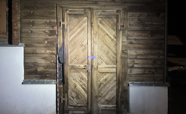 Feuer an Holztüre eines leerstehenden Holzhauses