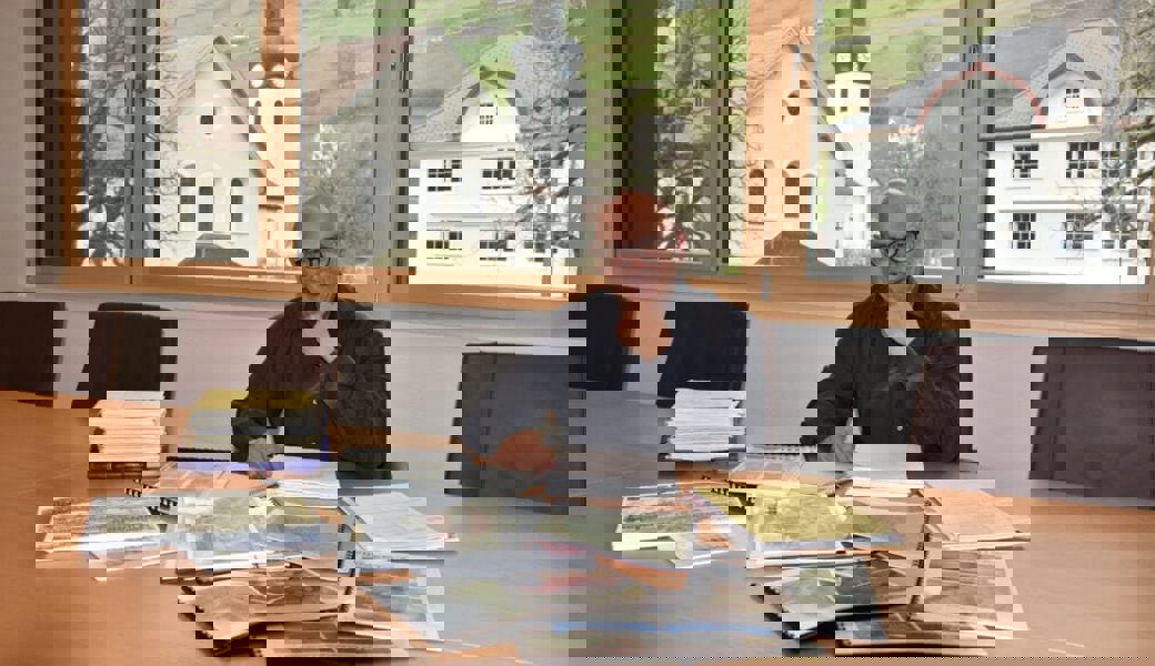  Rolf Züllig sitzt vor den Unterlagen der Hotel-Acker-Projekten. 