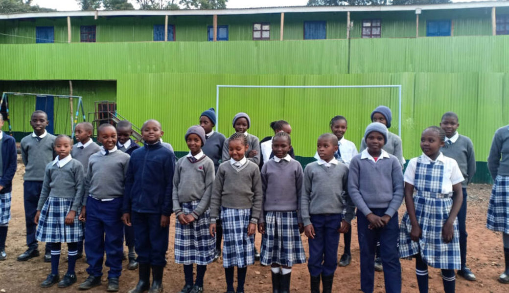  Die Schülerinnen und Schüler stellen sich stolz vor ihrer neuen Schule auf. 