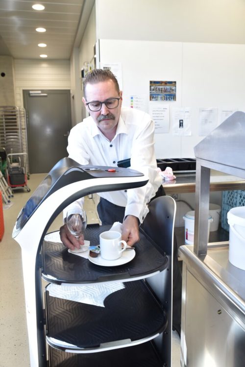  Peter Hofstetter, CEO der Gruppe Thurau, entnimmt dem Roboter das Geschirr, das er zur Abwaschstation gefahren hat.
