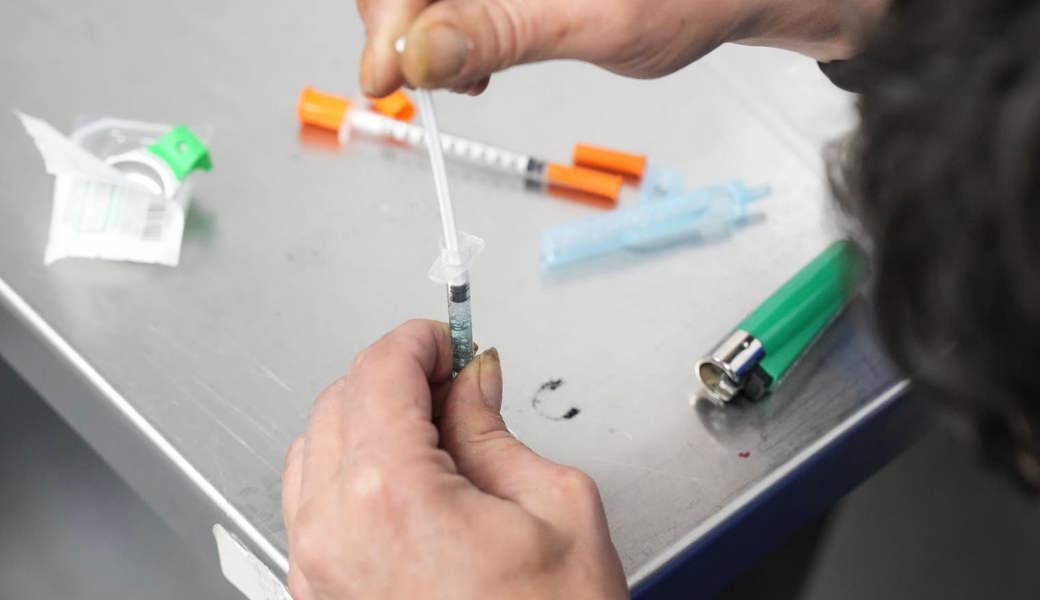 Eine suchtbetroffene Person bereitet in einem geschützten Konsumraum eine Spritze vor. 