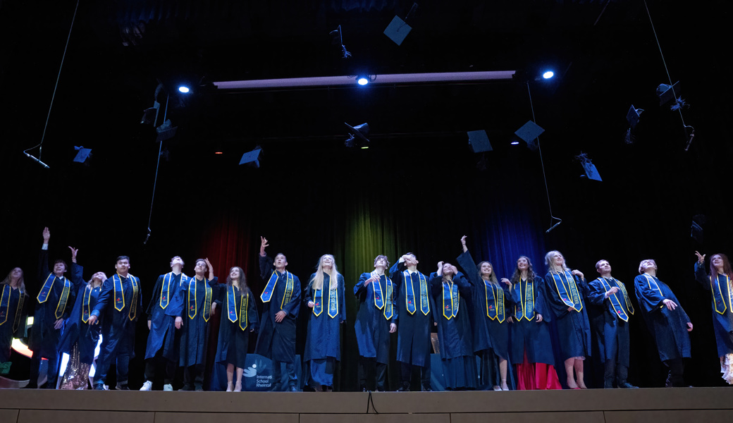 Die Absolventinnen und Absolventen werfen ihre Hüte in die Luft.