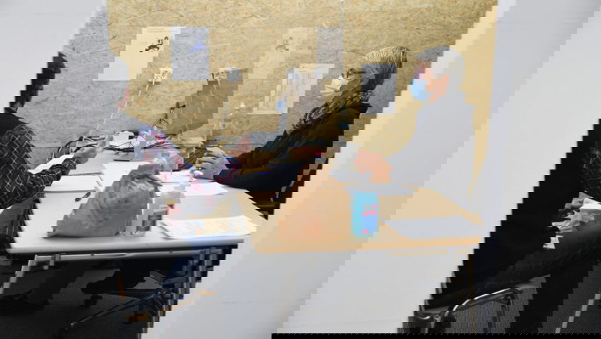  Eine Mitarbeiterin des Migrationsamtes befragt via Dolmetscher einen Migranten.