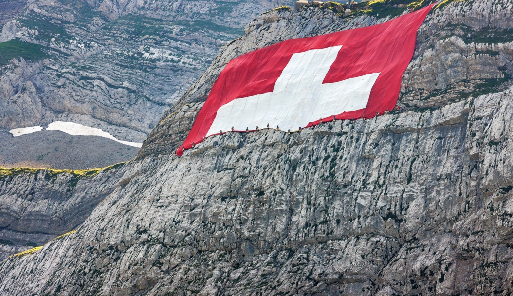 Höhenarbeiter der Geo-Höhenarbeiter AG hängen die Schweizerfahne an die Felswand.