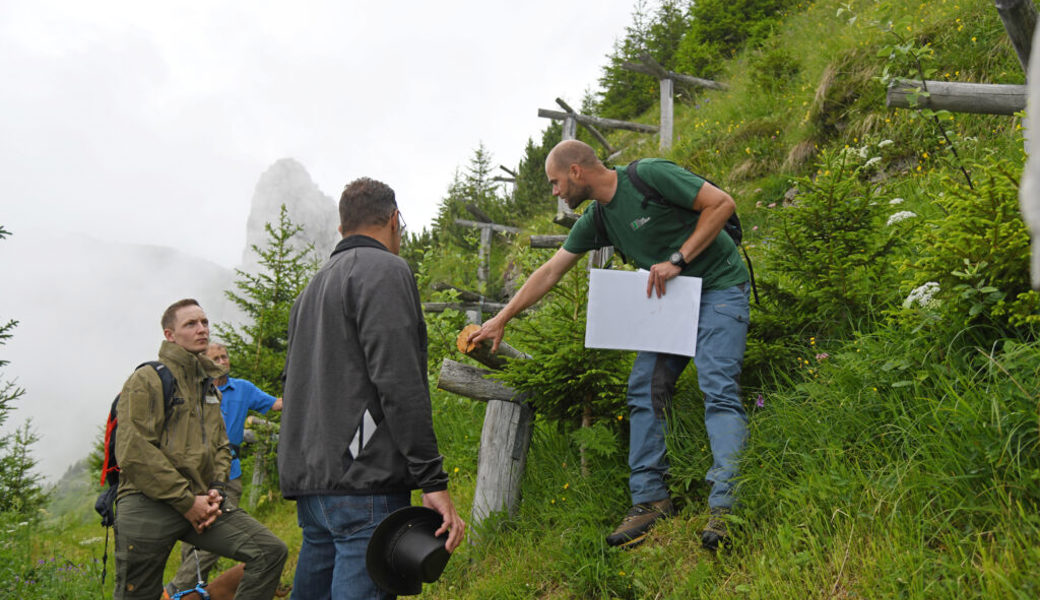  Revierförster Simon Zürcher (rechts) zeigt an einem 15 bis 20 Jahre alten Dreibeinbock, dass das verwendete Holz sehr dauerhaft ist. 