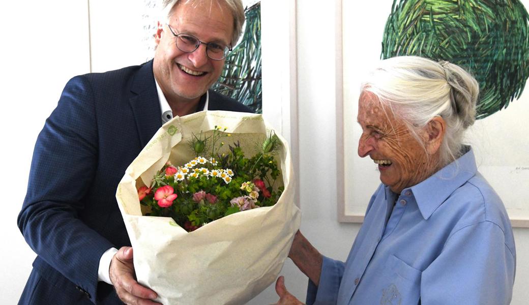 Gemeindepräsident Eduard Neuhaus überreicht der Jubilarin einen Blumenstrauss.