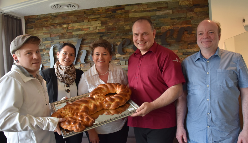 Manuel Hinder (links) und Philipp Metzger (Zweiter von rechts) nehmen den Schlüssel aus Zopfteig von Imelda (Mitte) und Stephan Schweizer (rechts) entgegen. Michèle Kottmann wird die Filiale führen.  